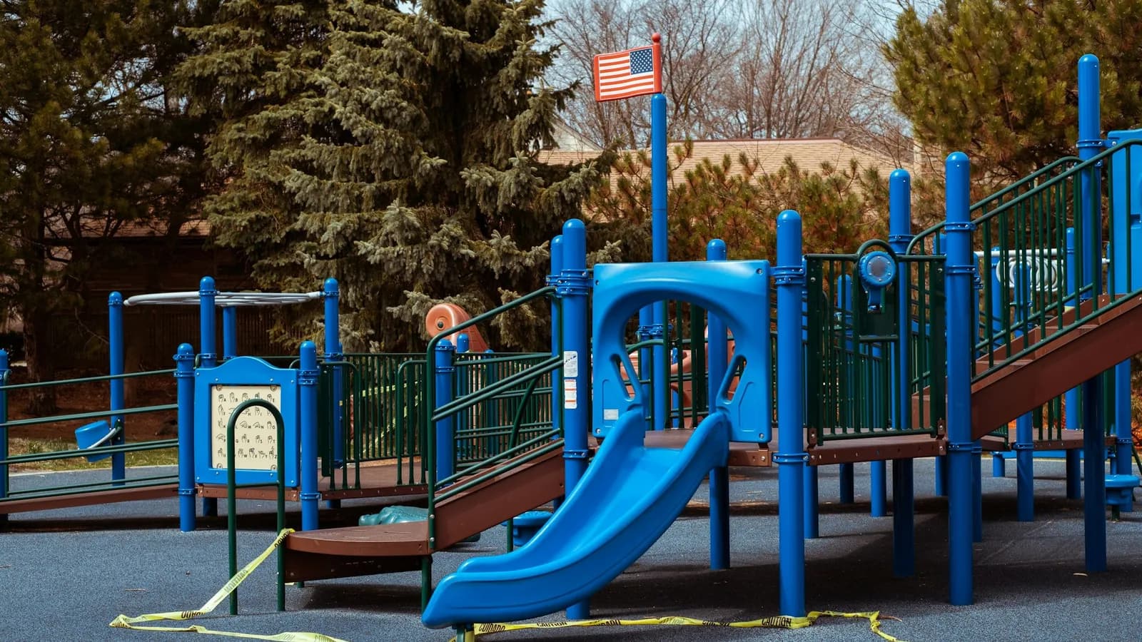 Empty playground structure with caution tape strung across the surfacing