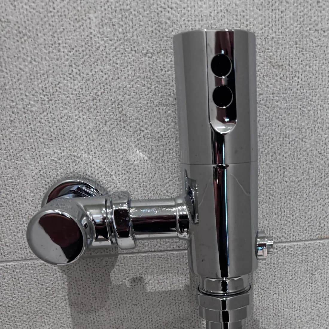 Chrome flush valve on a restroom fixture