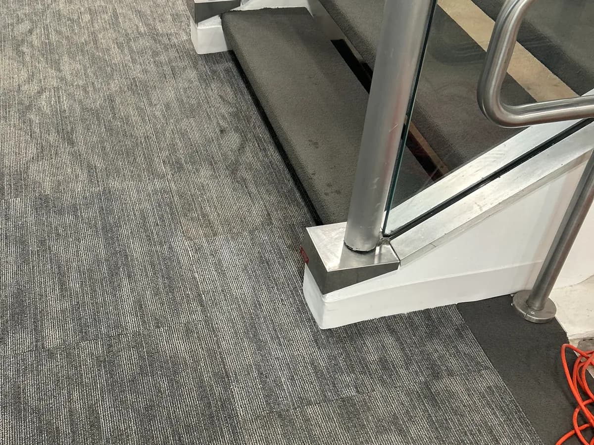 Stained carpet tiles at a stair landing replaced, after