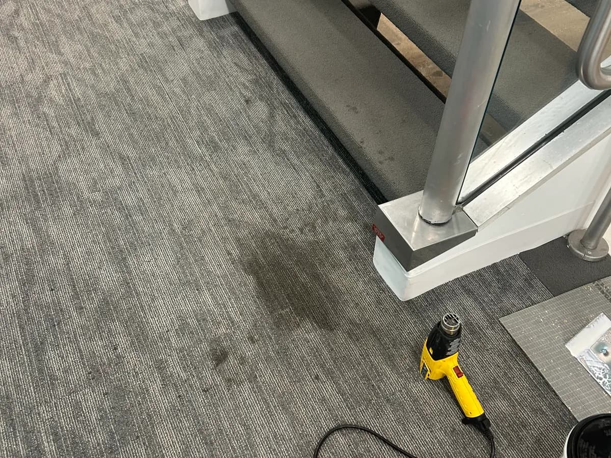 Stained carpet tiles at a stair landing replaced, before