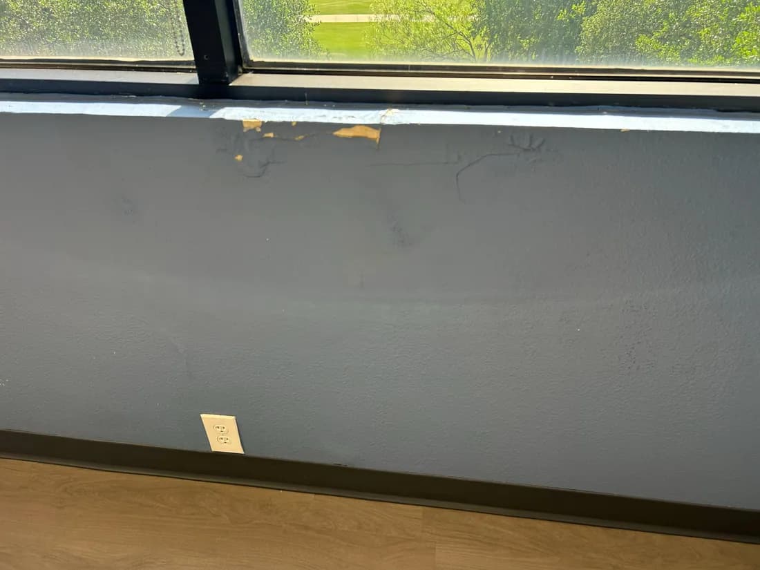 Damaged paint and wall finish below an interior window sill
