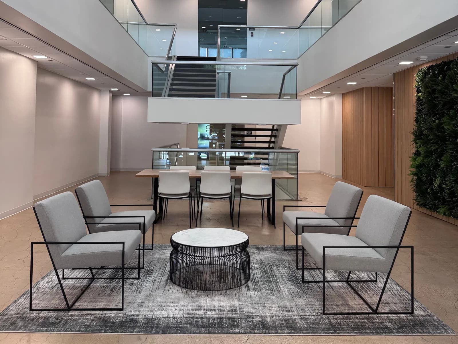 Two-story commercial office lobby with a seating area and glass railings